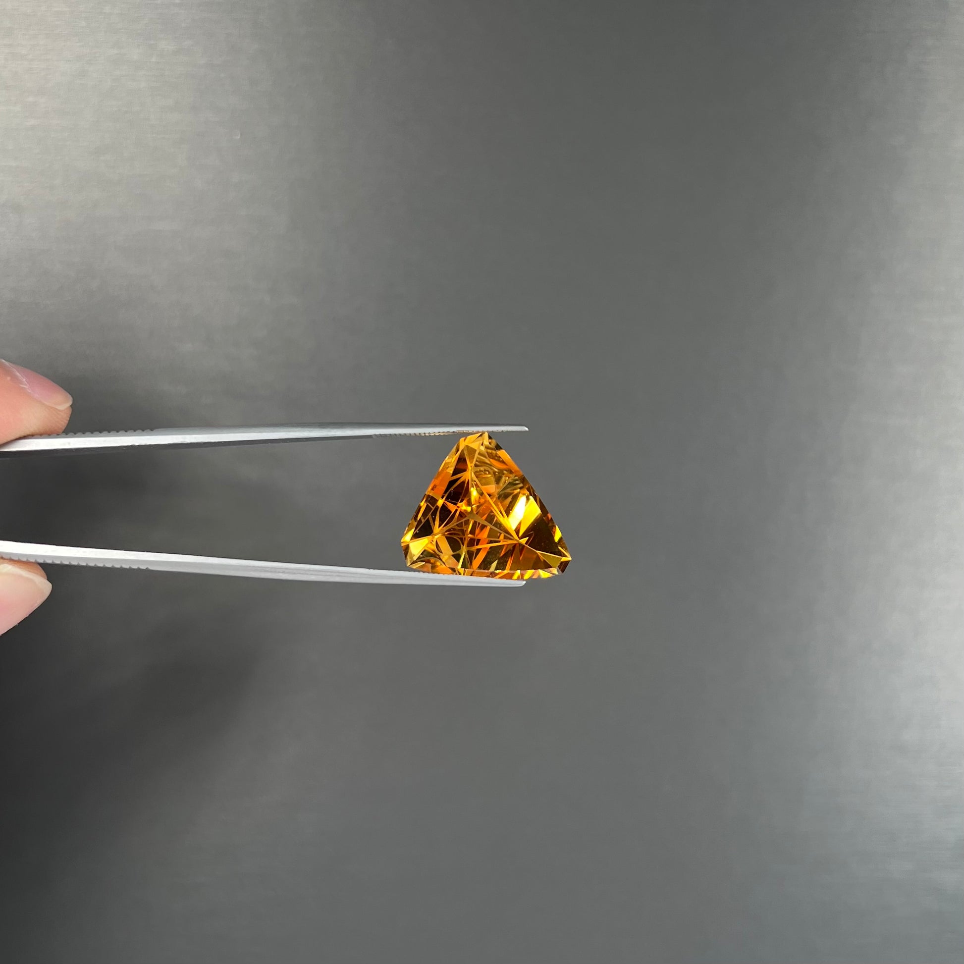 A loose, triangular fantasy cut yellow citrine stone cut by Arthur Lee Anderson.