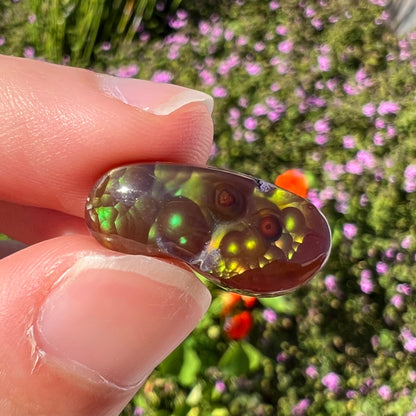 A loose, cabochon cut fire agate gemstone.  The stone resembles a foot with a green heel and yellow toes.