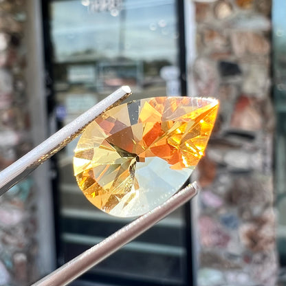 A loose, golden yellow, pear shaped citrine gemstone.