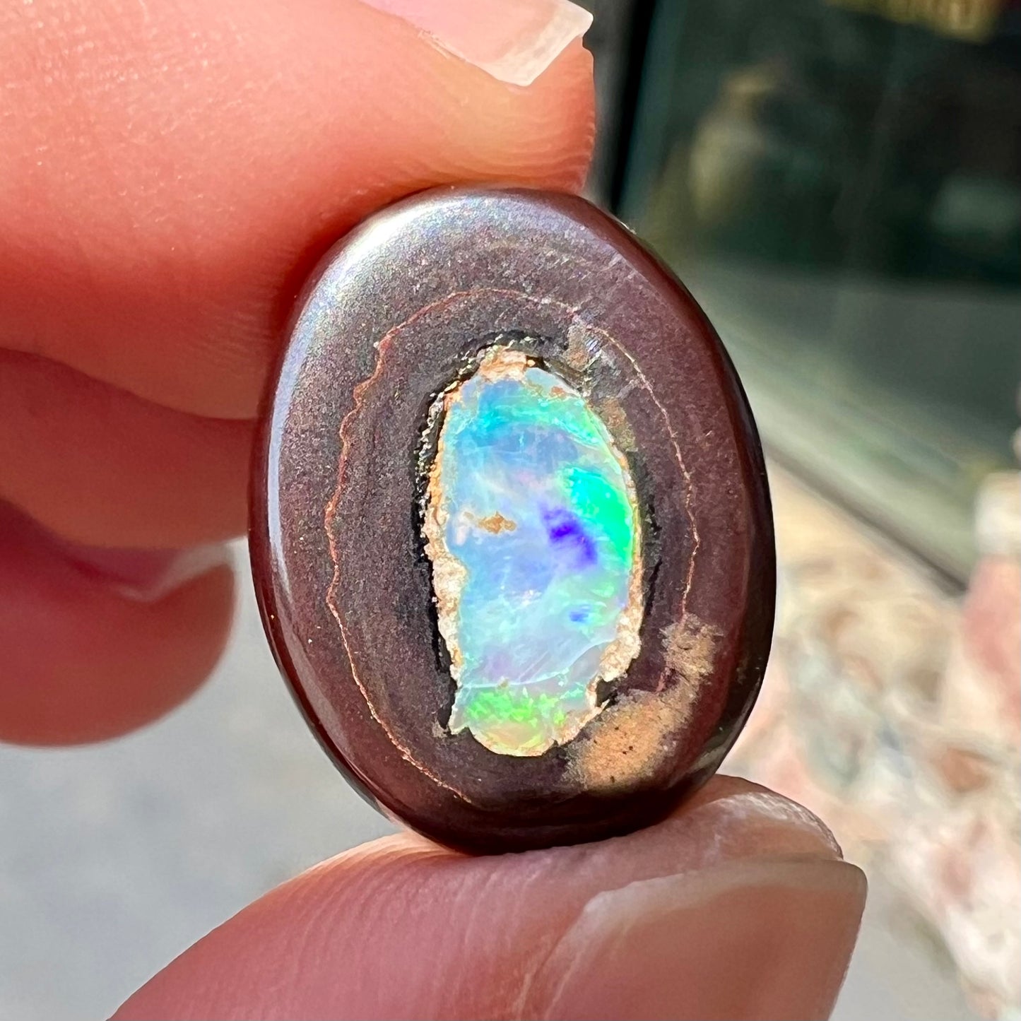 A polished Yowah nut opal stone.  The opal shines blue and green colors.