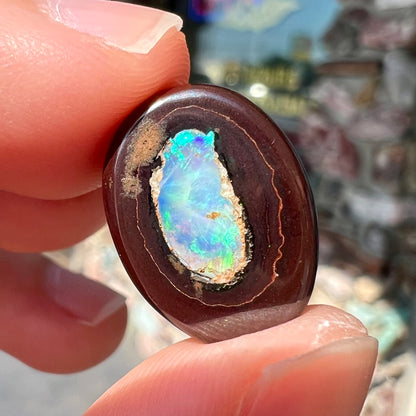 A polished Yowah nut opal stone.  The opal shines blue and green colors.