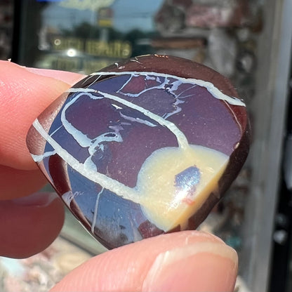 A polsihed, freeform Yowah nut opal specimen.  The stone is ironstone with common opal potch inclusions.