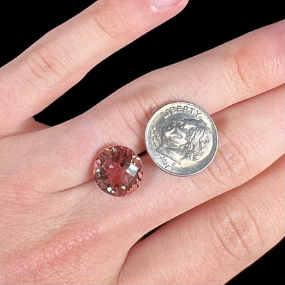 A loose, round brilliant checkerboard cut Zandrite gemstone.  The stone changes colors from greenish tan to purple.