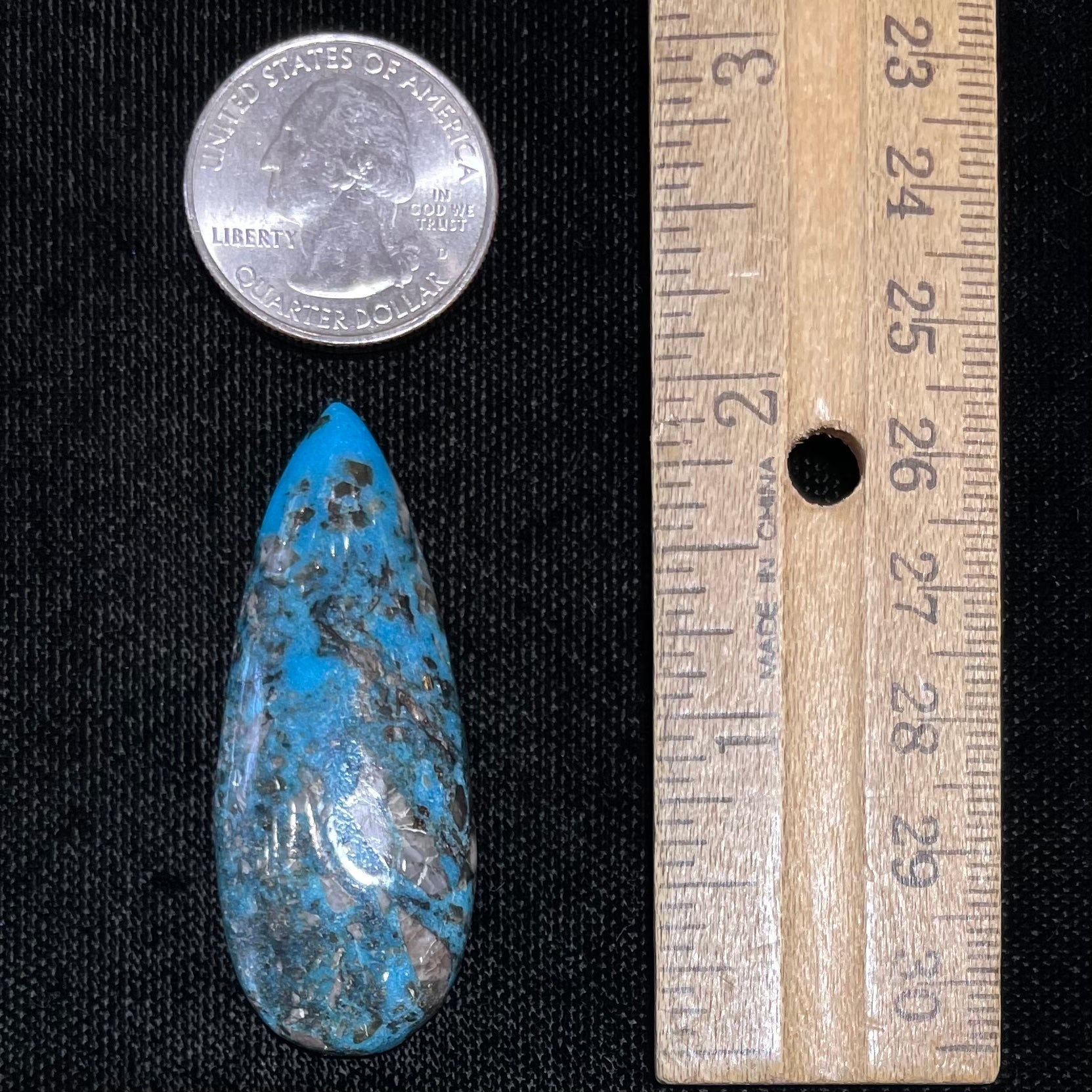 A loose, teardrop shaped, cabochon cut turquoise stone from Kingman, Arizona.  Pyrite inclusions can be seen.