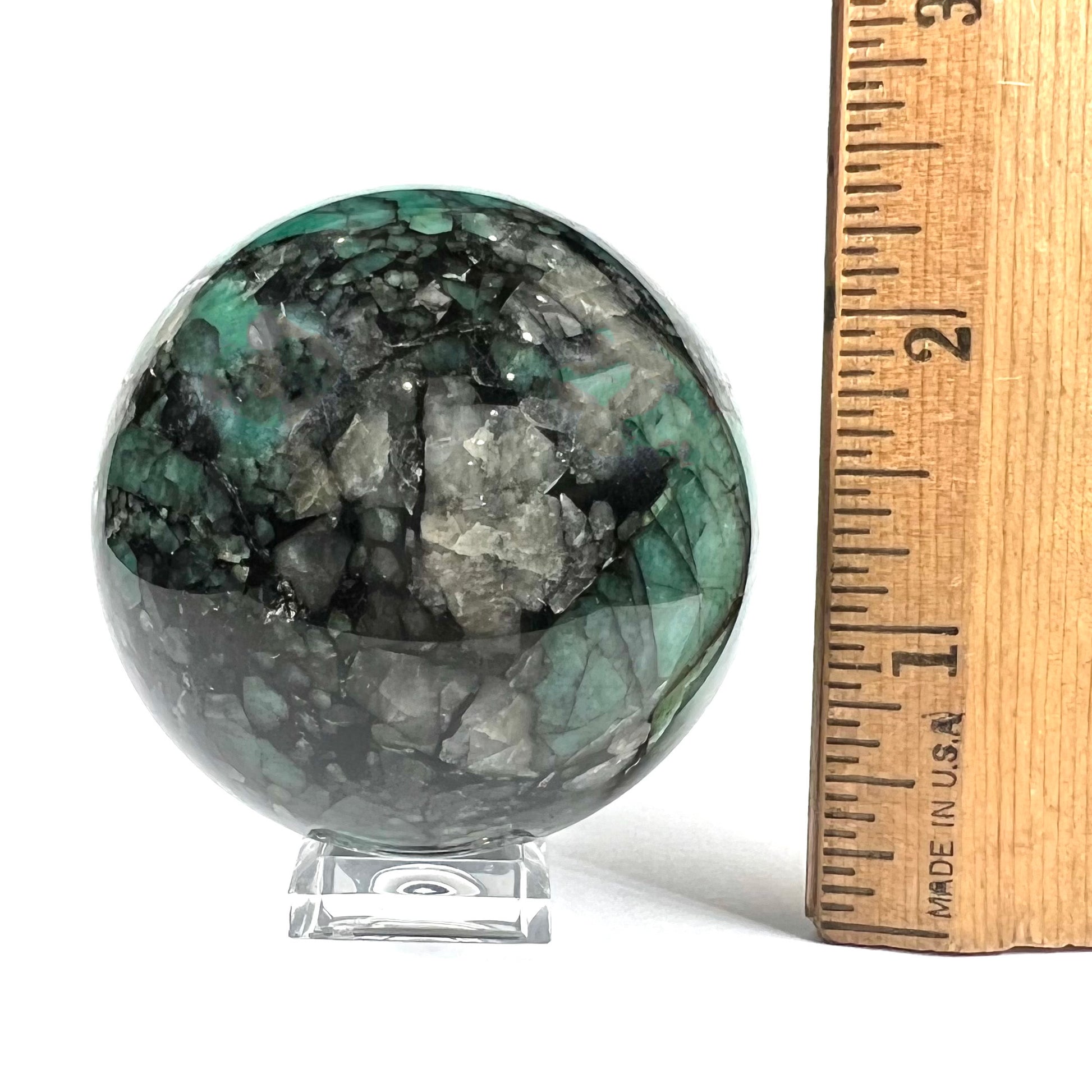 A gemstone sphere carved from a natural emerald crystal specimen, measuring 2.2 inches in diameter.