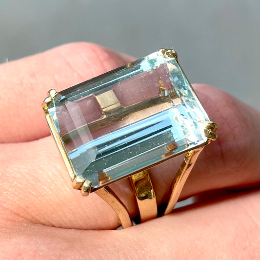 Large ladies' emerald cut aquamarine solitaire cocktail ring in yellow gold.