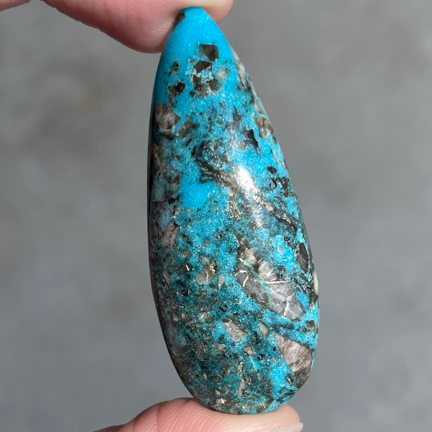 A loose, teardrop shaped, cabochon cut turquoise stone from Kingman, Arizona.  Pyrite inclusions can be seen.