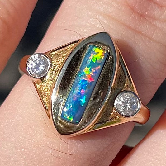 Lightning Ridge black opal set between two round diamonds in an 18 karat yellow gold ring.  Anaheim, California.