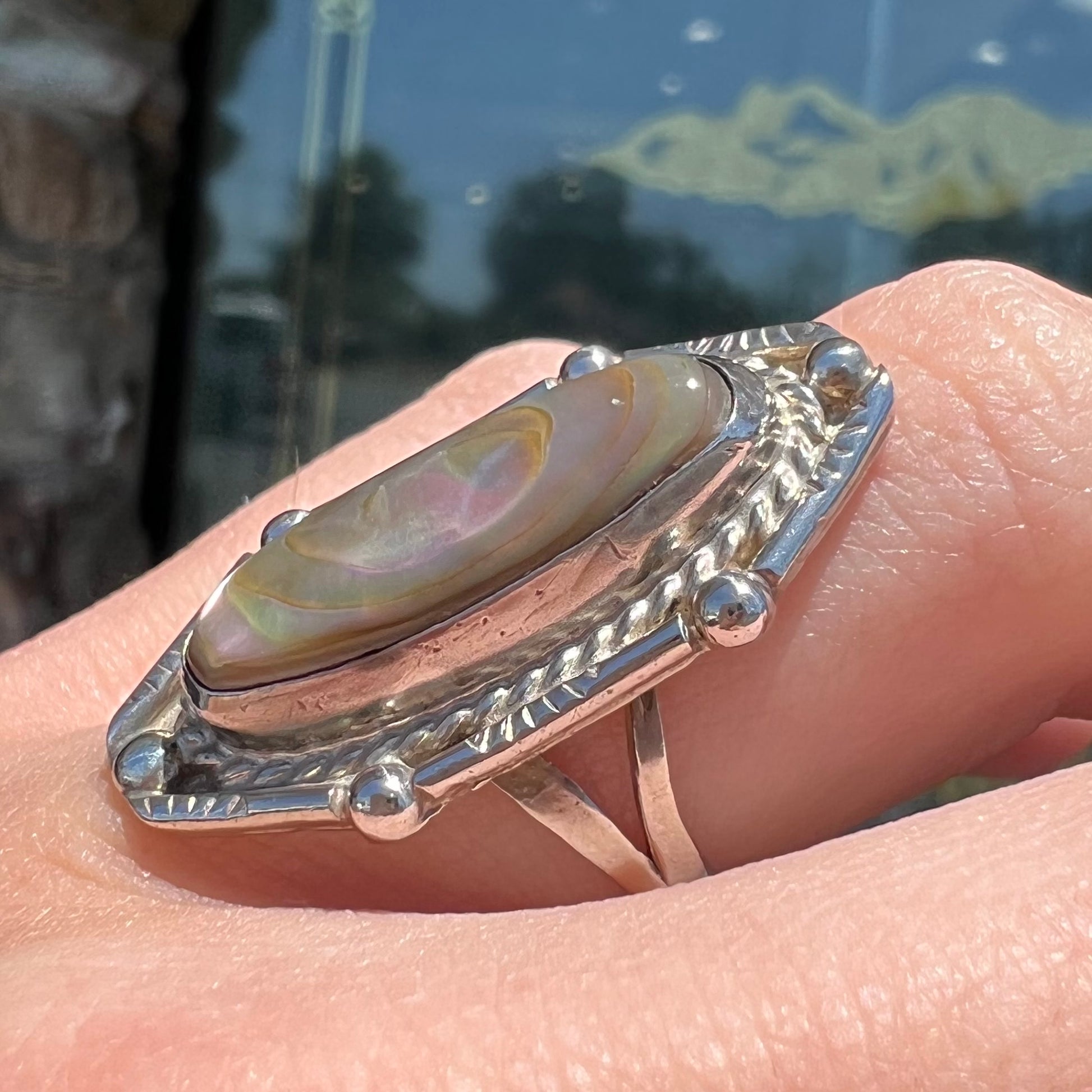 A Southwest style sterling silver ring set with a pink, oval cabochon cut mother of pearl shell.