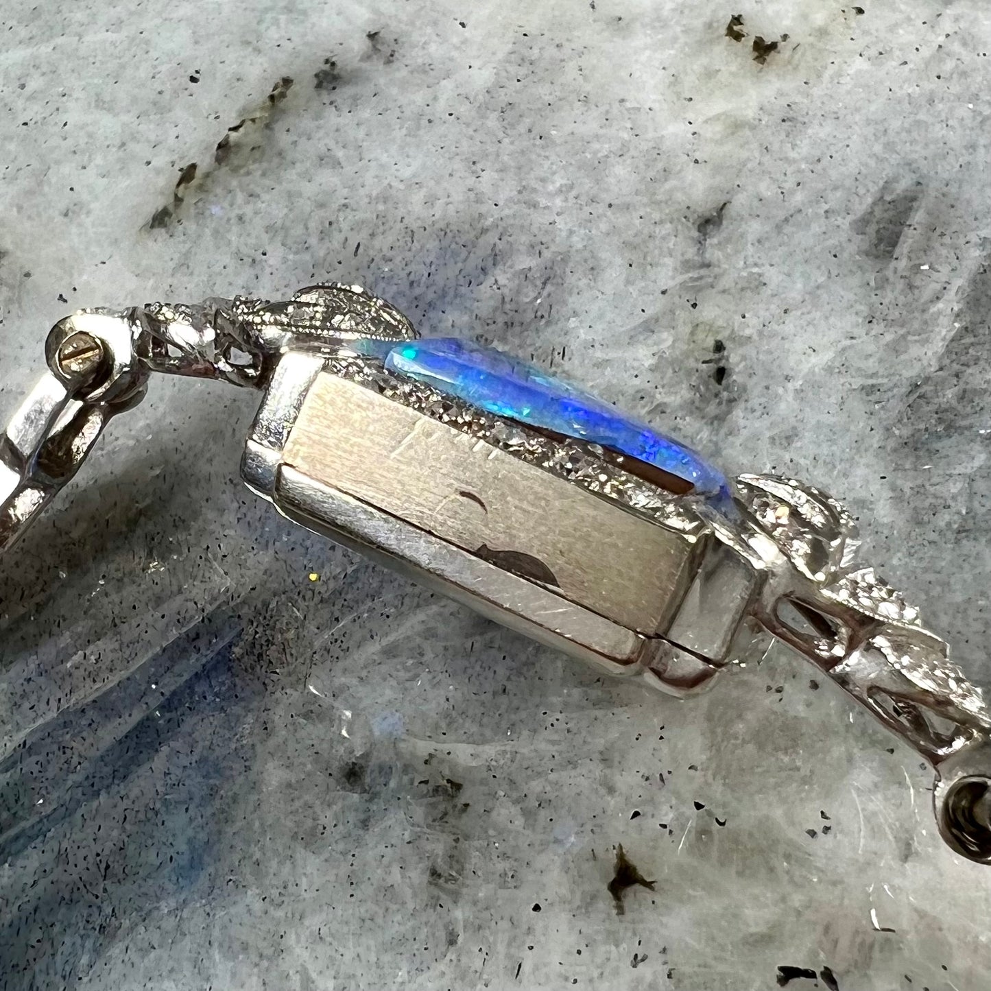 A vintage, art deco style white gold and diamond bracelet set with a rectangular shape black boulder opal stone.