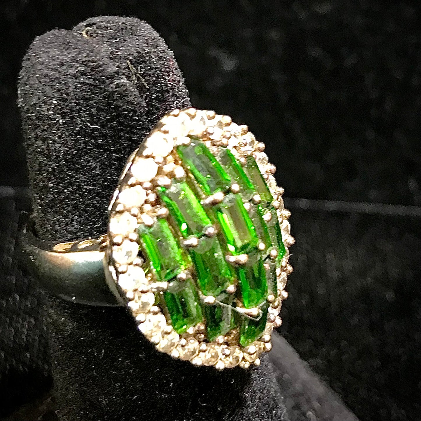 A sterling silver marquise shape ring set with green baguette cut stones.