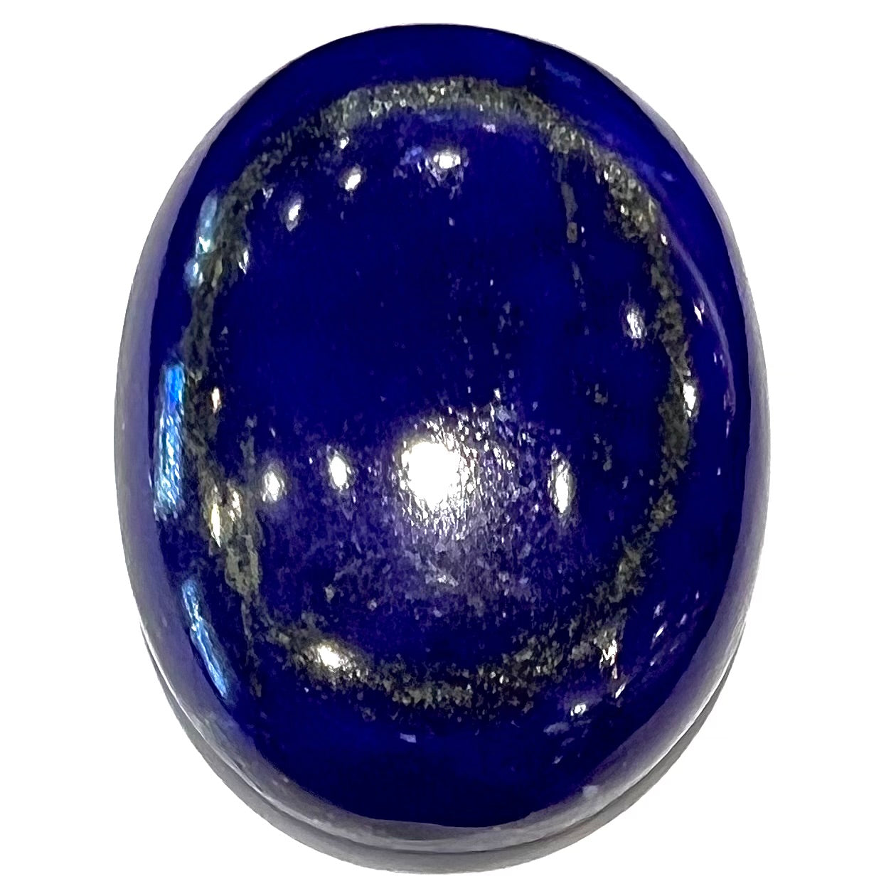 A loose, oval cabochon cut lapis lazuli stone.  A circle of pyrite inclusions is seen on the front.