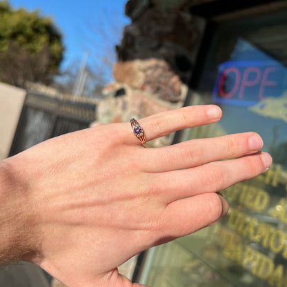 A ladies split shank gold ring set with an oval cut amethyst and round brilliant diamond accents.