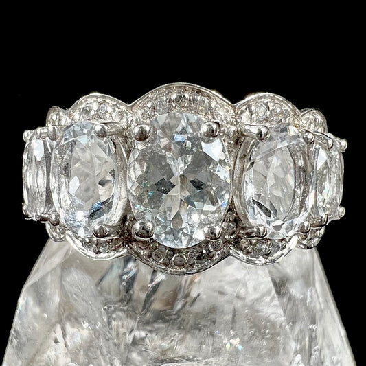 A silver five stone oval cut aquamarine and diamond halo ring.