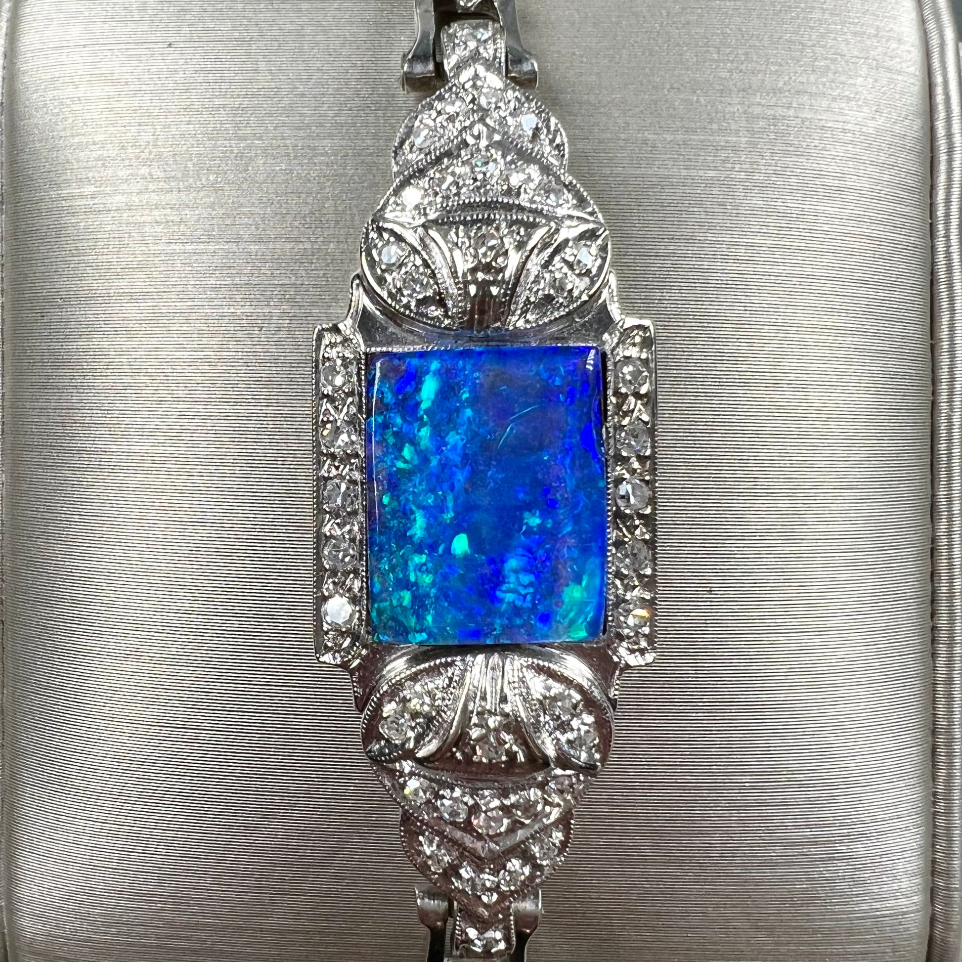 A vintage, art deco style white gold and diamond bracelet set with a rectangular shape black boulder opal stone.