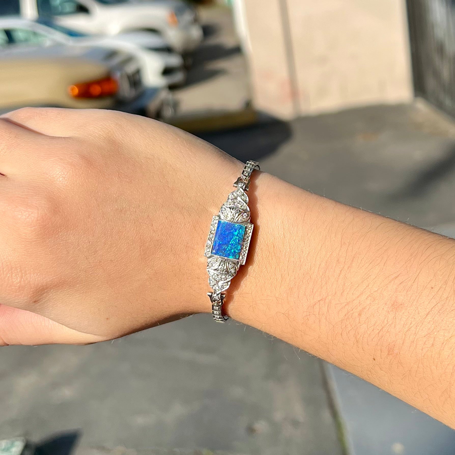 A vintage, art deco style white gold and diamond bracelet set with a rectangular shape black boulder opal stone.