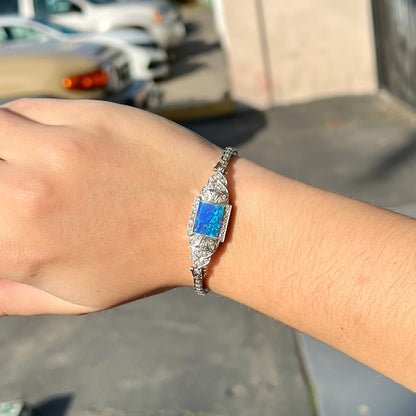 A vintage, art deco style white gold and diamond bracelet set with a rectangular shape black boulder opal stone.