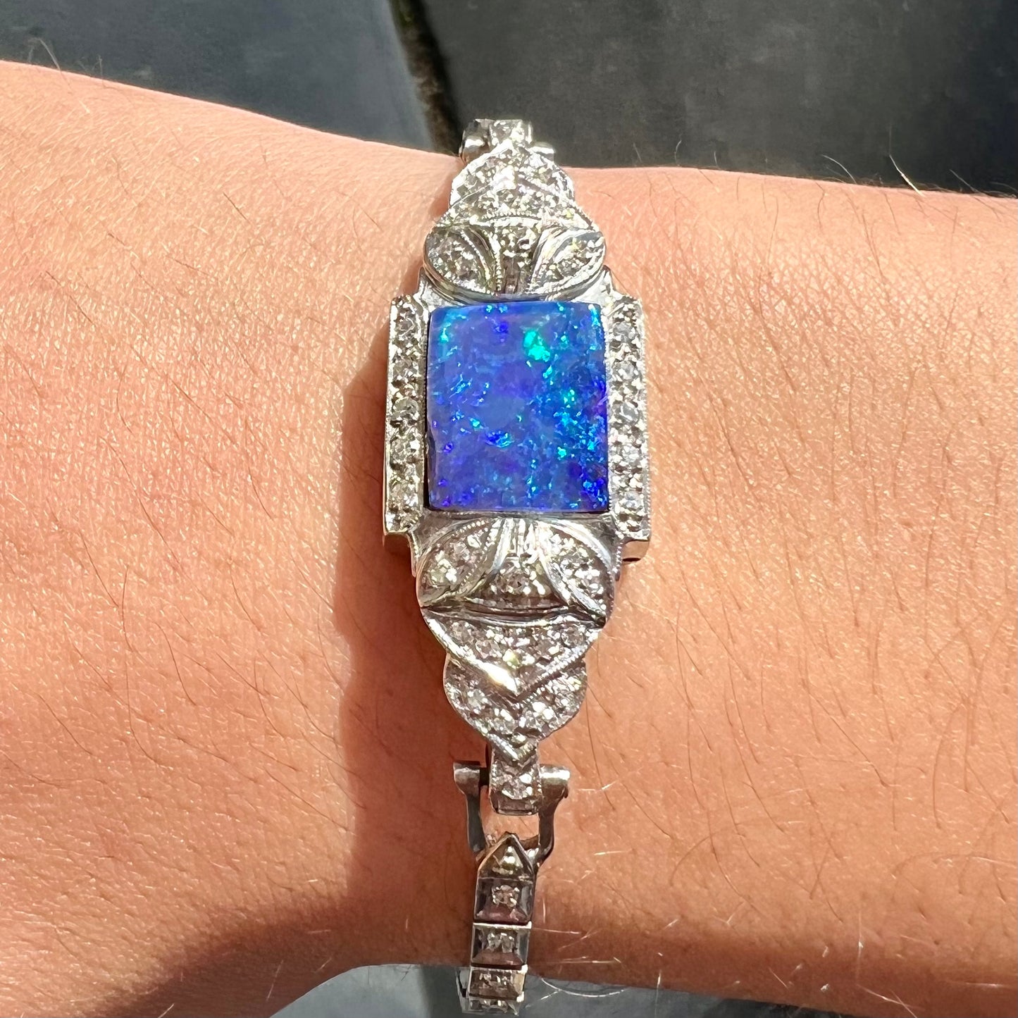 A vintage, art deco style white gold and diamond bracelet set with a rectangular shape black boulder opal stone.