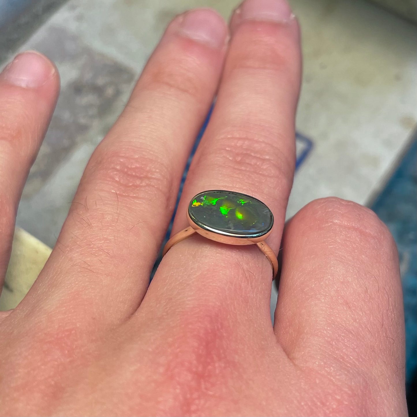 A handmade Lightning Ridge black opal solitaire ring in yellow gold.  Fire is green.