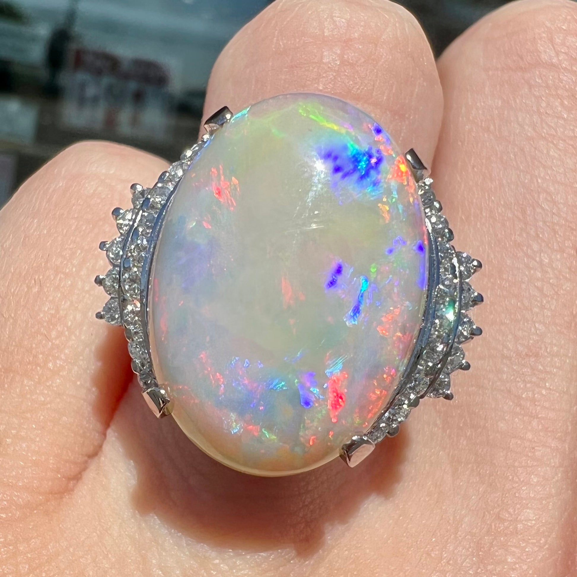 An oval cabochon cut Coober Pedy, Australian opal prong set in a platinum ring with round cut diamonds.