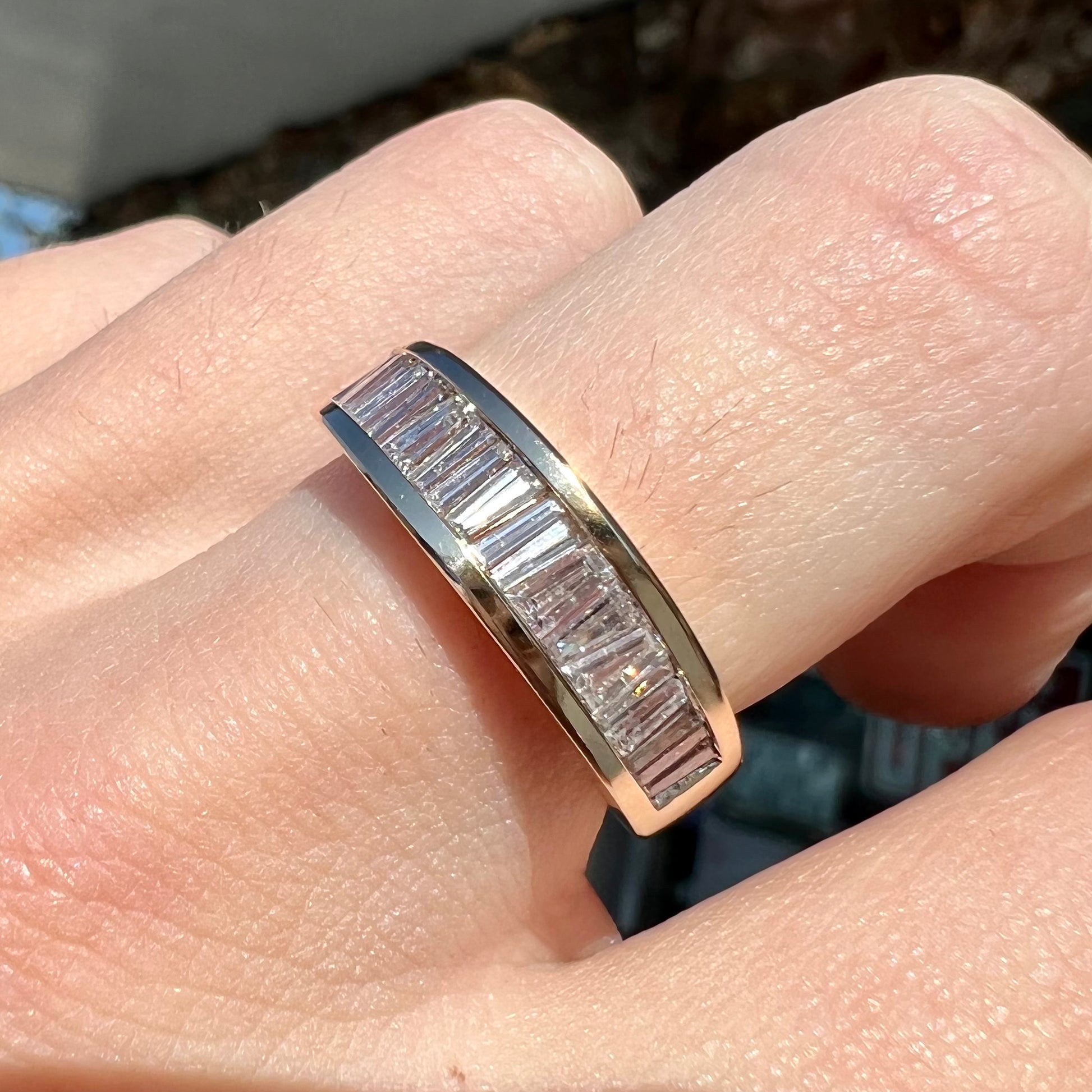 A ladies' yellow gold ring channel set with a row of baguette cut diamonds.