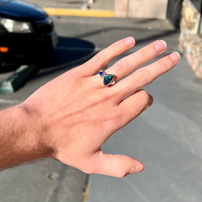 A ladies' white gold ring set with Australian black boulder opal and pear shape blue sapphire.