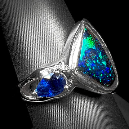 A ladies' white gold ring set with Australian black boulder opal and pear shape blue sapphire.