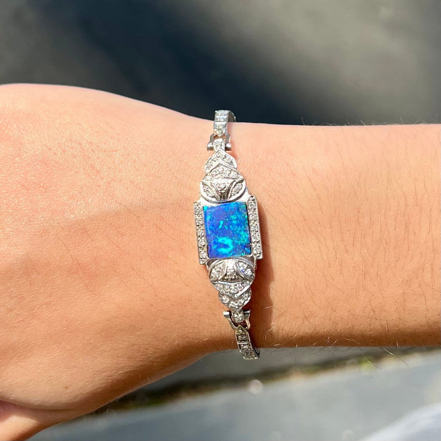 A vintage, art deco style white gold and diamond bracelet set with a rectangular shape black boulder opal stone.