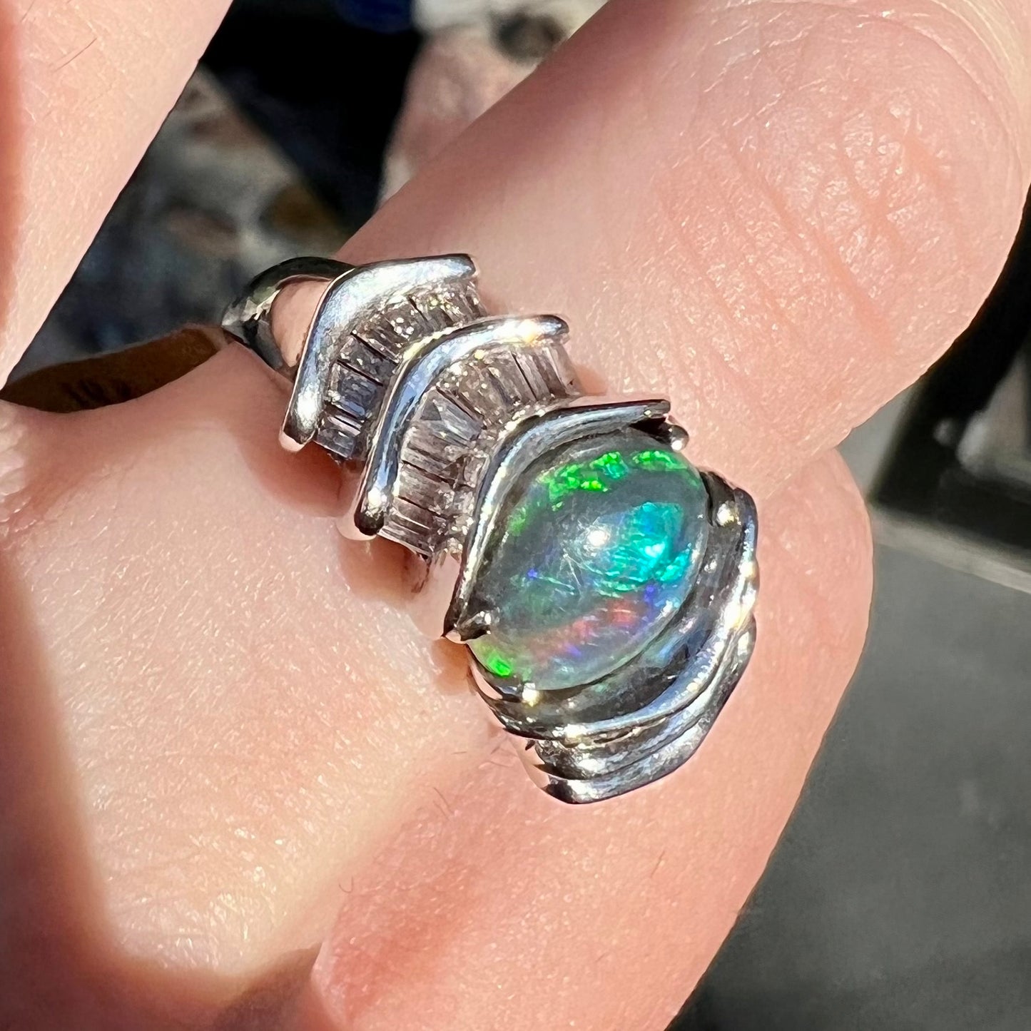 A white gold ring set with a Lightning Ridge black opal and baguette cut diamonds.