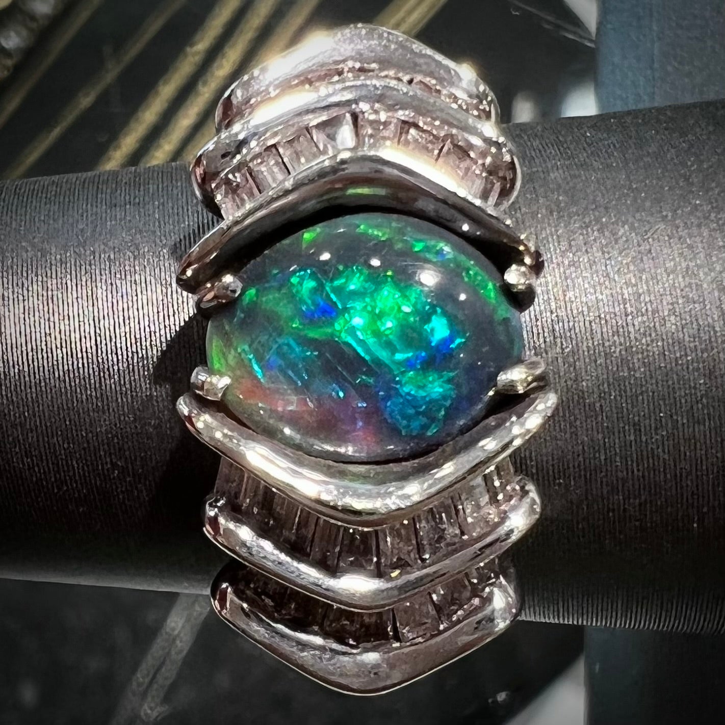 A white gold ring set with a Lightning Ridge natural black opal and baguette cut diamonds.