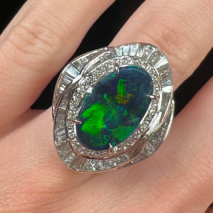 A ladies' platinum diamond halo ring set with a natural black opal stone from Lightning Ridge, Australia.