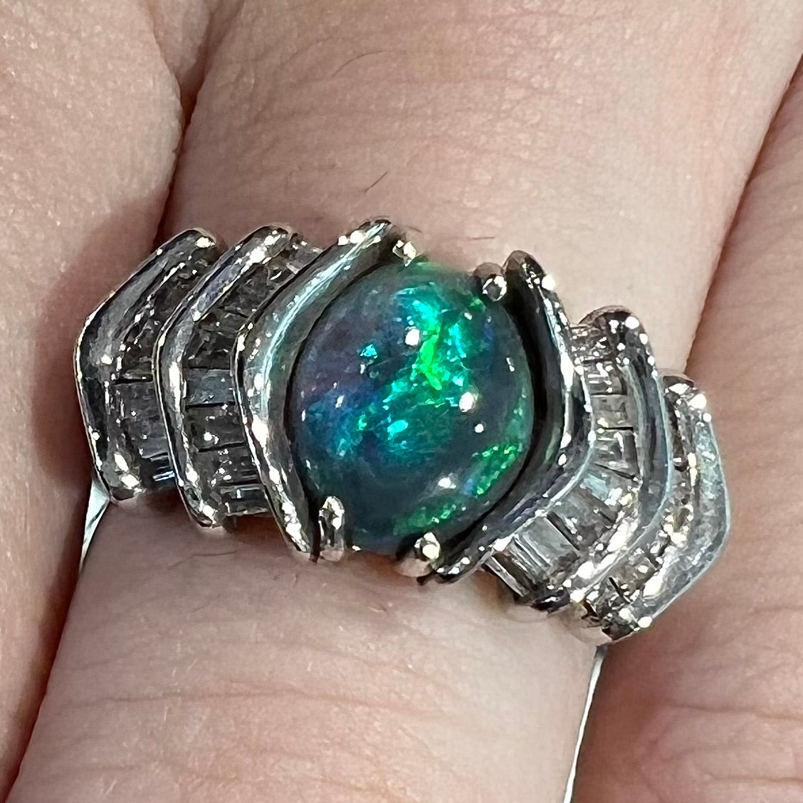 A white gold ring set with a Lightning Ridge black opal and baguette cut diamonds.