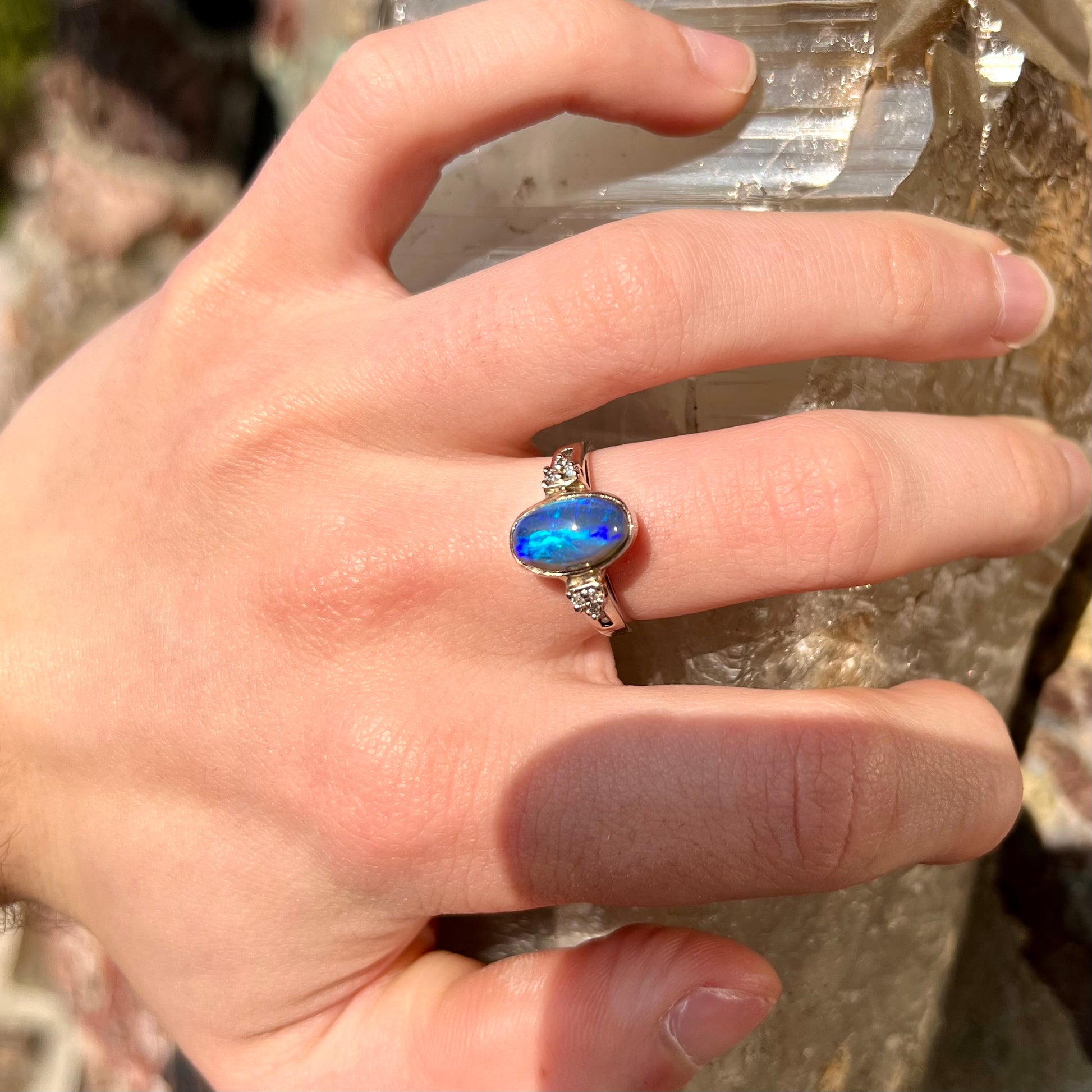 A white gold ring set with a Lightning Ridge black opal and diamond accents.  The opal displays a cat's eye pattern.