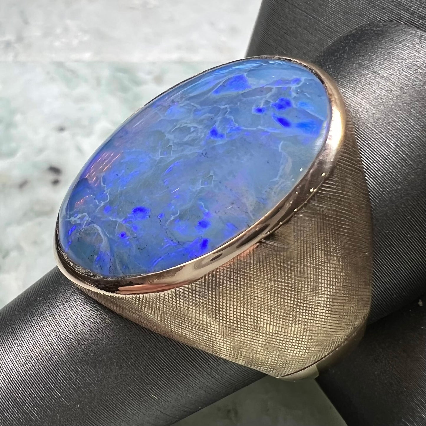 A Lightning Ridge black opal men's ring in solid yellow textured gold.