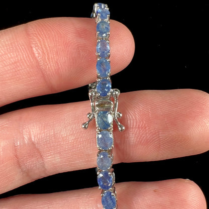 A sterling silver tennis bracelet set with faceted oval cut blue sapphires.