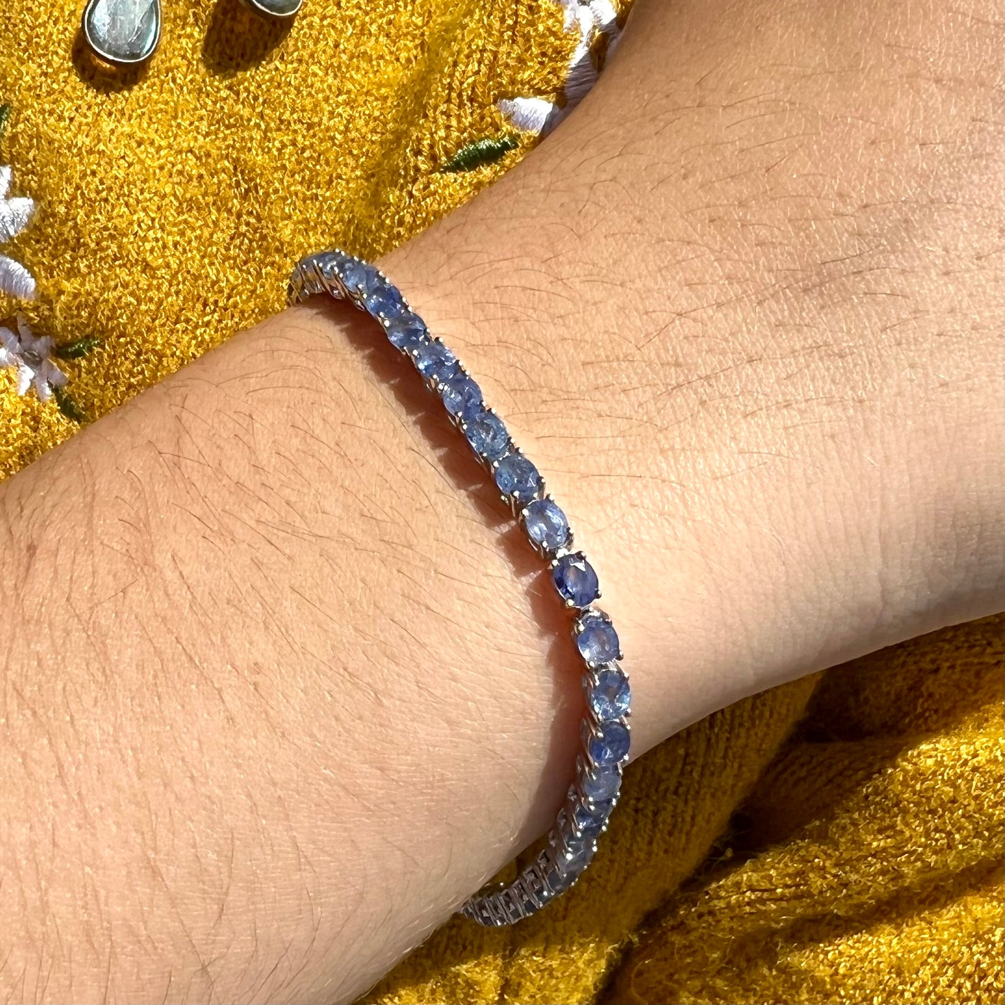 A sterling silver tennis bracelet set with faceted oval cut blue sapphires.