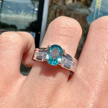 A sterling silver ring set with an oval cut blue zircon center stone and channel set white zircon accents.