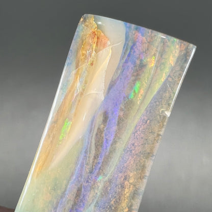 A polished, tapered rectangular cut boulder opal stone from Quilpie, Australia.