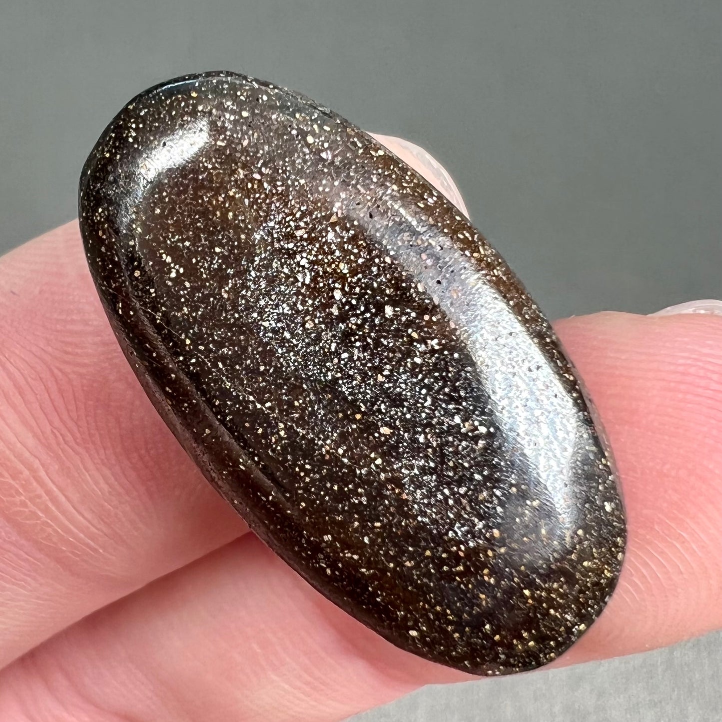 A loose, oval cabochon cut boulder opal stone from Queensland, Australia.