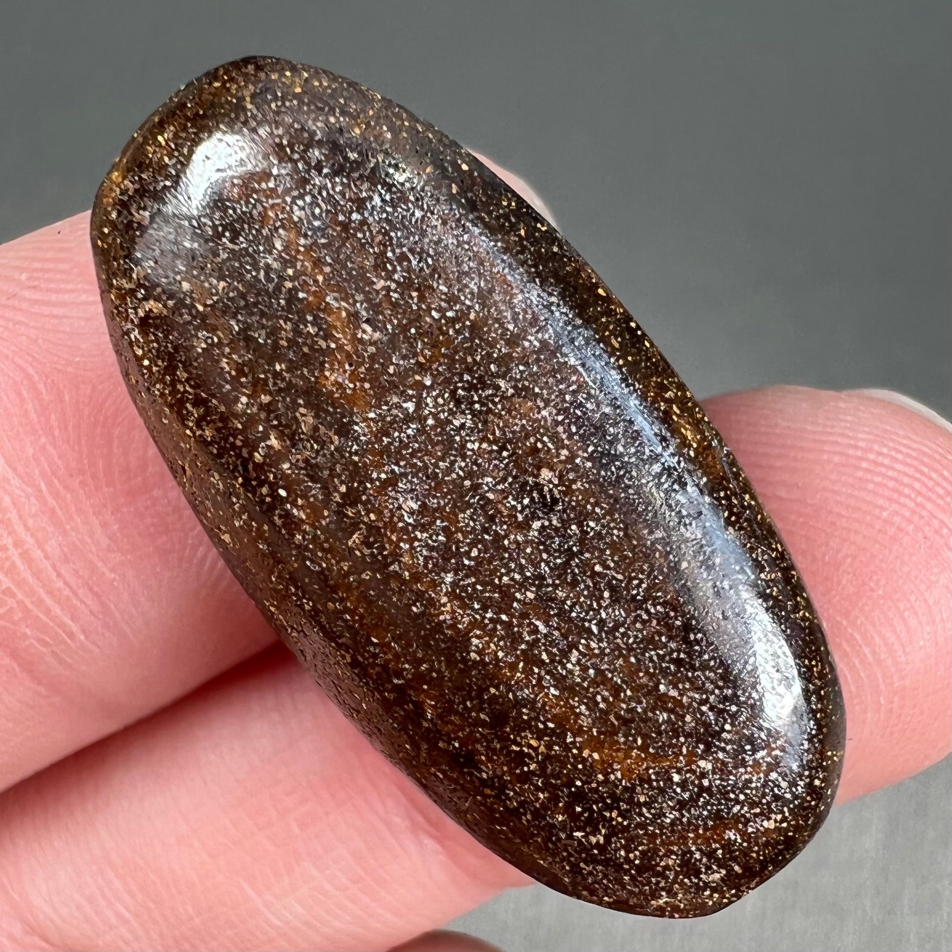 A loose, oval cabochon cut boulder opal stone from Queensland, Australia.