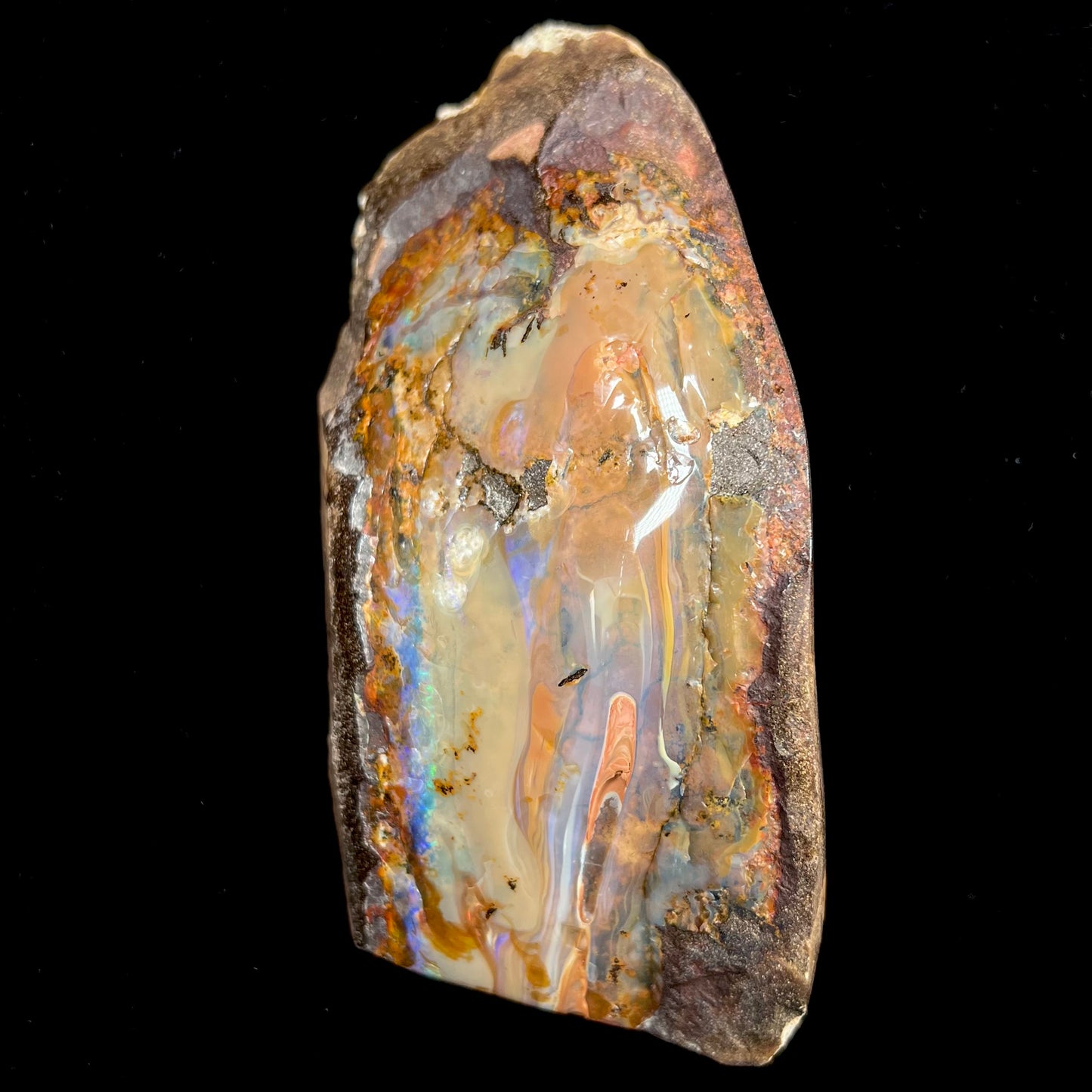 A polished Quilpie boulder opal specimen.  The stone has a stripe of bright blue, green, and purple.