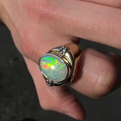 A yellow gold men's opal ring set with princess cut white sapphires.