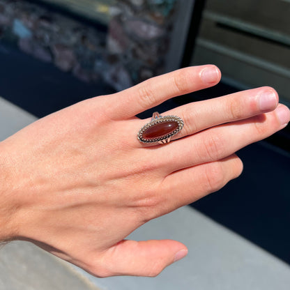 A split shank silver ring set with a brown sard stone in a rope bezel with small prongs.