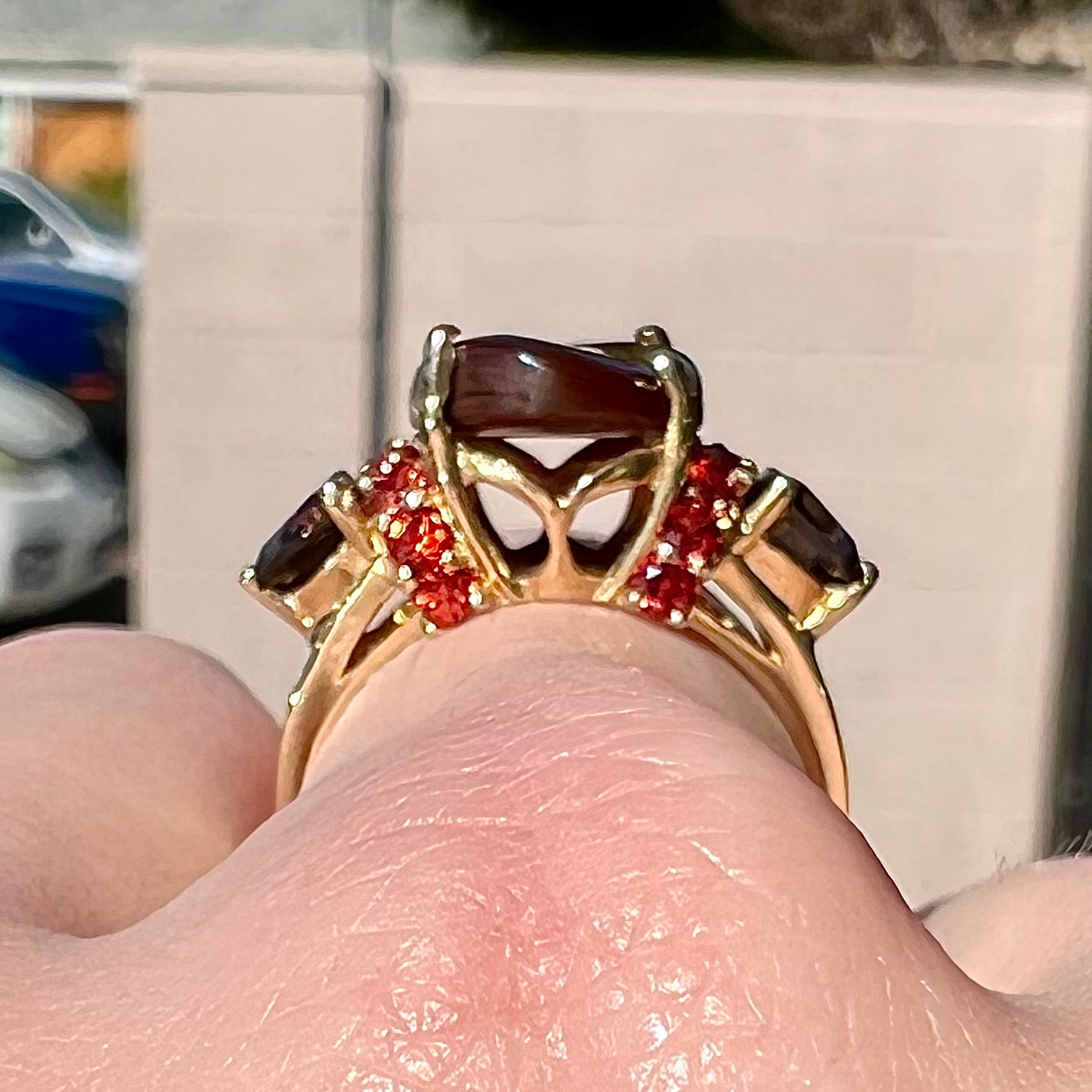 A ladies yellow gold fire agate ring set with trillion cut smoky quartz and round cut red-orange garnet accents.  The fire agate displays green and red.