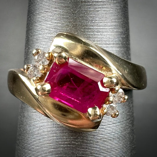 Emerald cut Burma ruby and diamond ring set in 14 karat yellow gold.