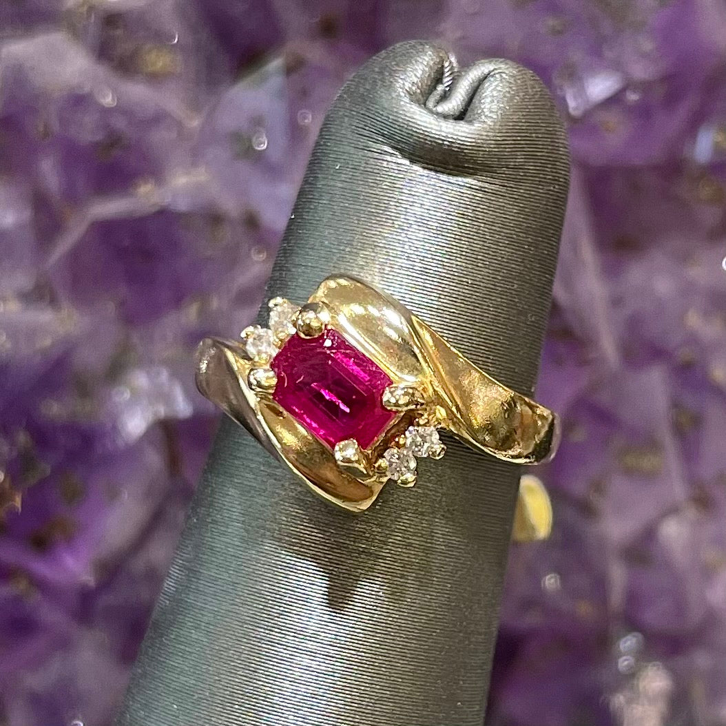 Emerald cut Burma ruby and diamond ring set in 14 karat yellow gold.