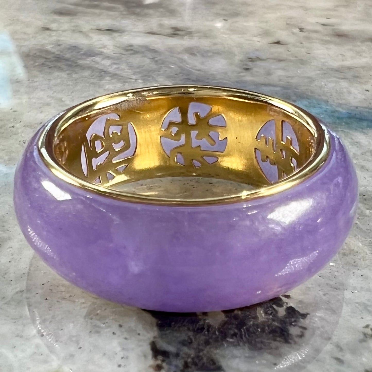 A stone ring carved from purple jadeite jade and mounted on a gold band.