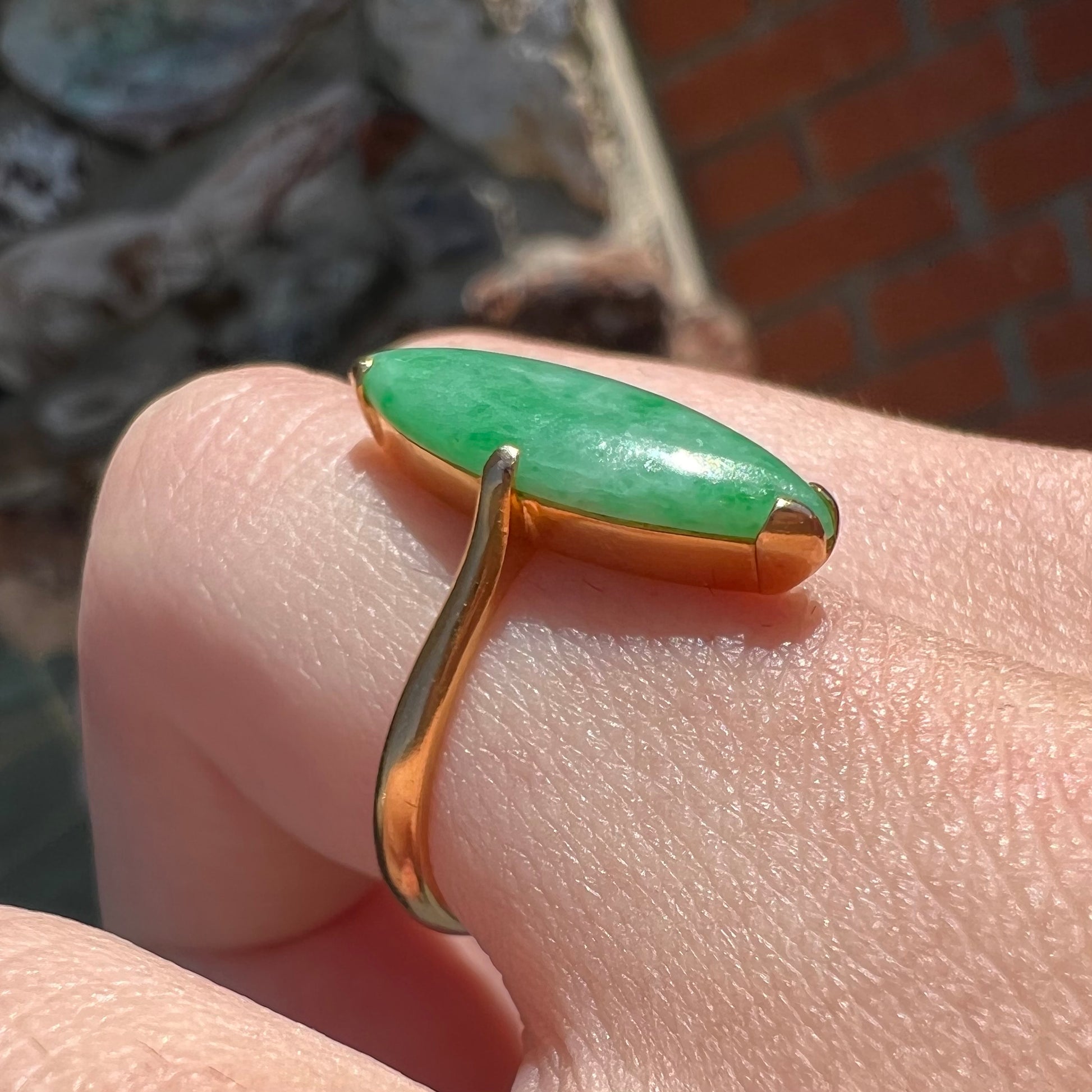 A 22 karat yellow gold solitaire ring set with a marquise cabochon cut green jadeite.