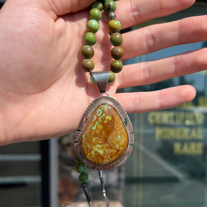 A handmade, likely Navajo silver pendant set with Kingman turquoise on a green Kingman turquoise beaded necklace.