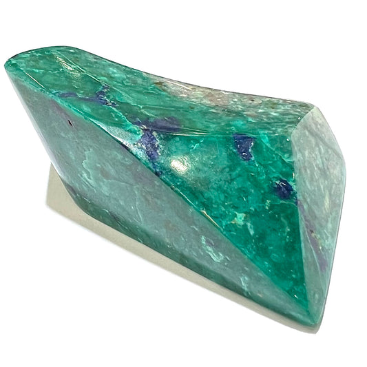 A loose polished sculpture of green chrysocolla with blue azurite inclusions.